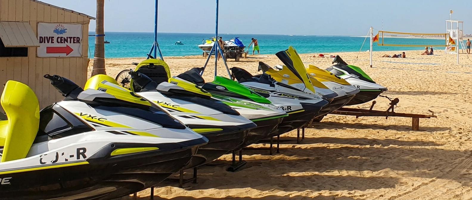 Sal - cabo verde - Jet skis coloridos alinhados na areia de praia, com mar azul ao fundo e centro de mergulho.