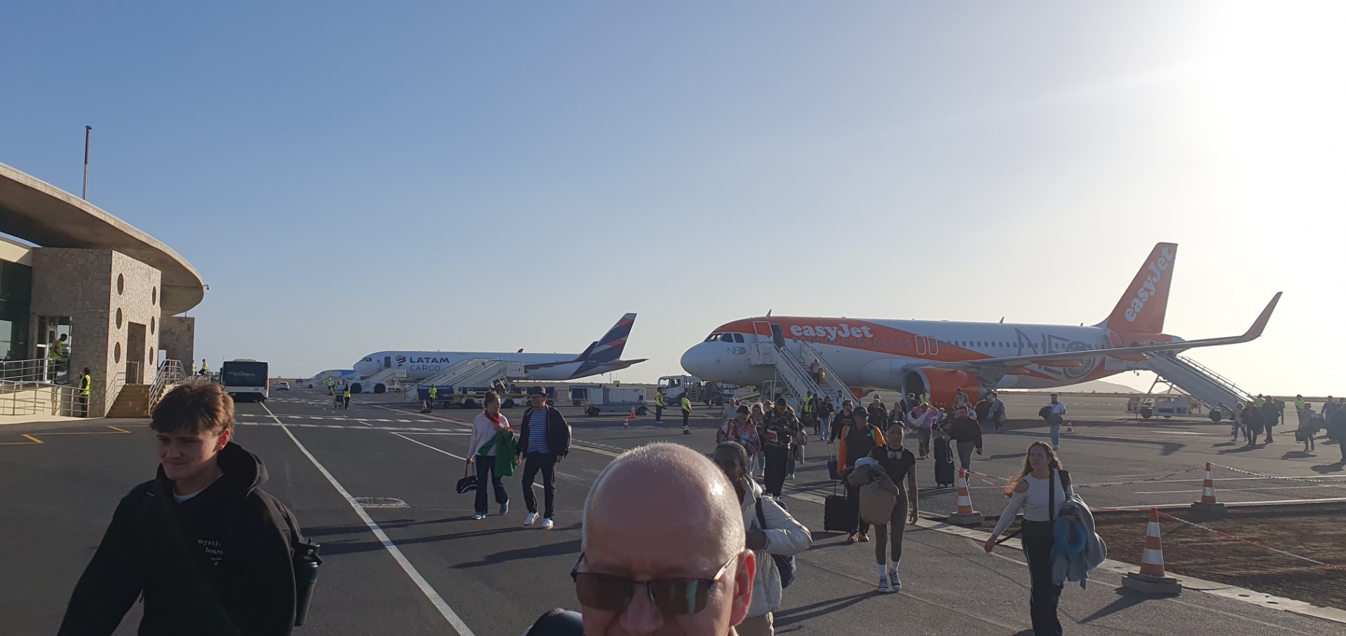 Flughafen Sal - Passagiere gehen auf dem Rollfeld an einem easyJet-Flugzeug vorbei, während Crew und Gepäckwagen bereitstehen.