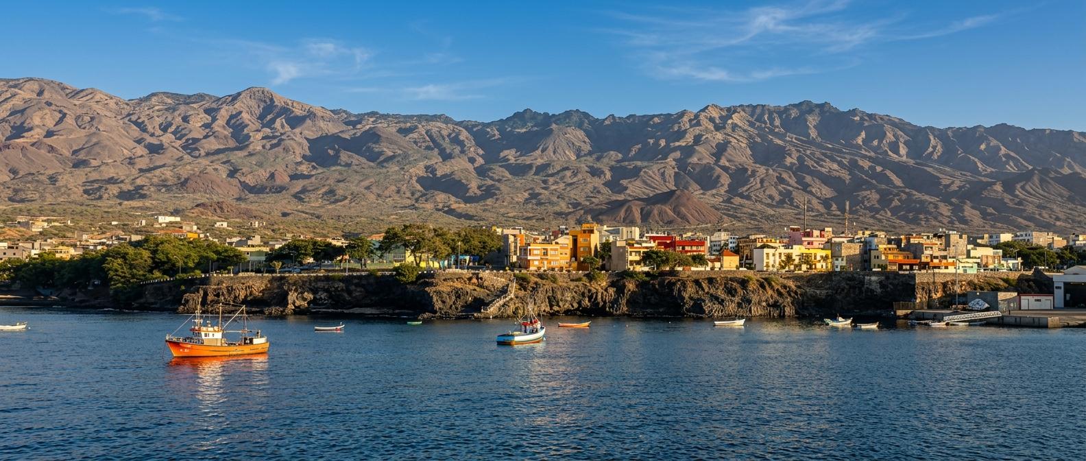 Porto Novo auf Santo Antão - Bucht mit Fischerbooten, Küstenstadt und hohen, trockenen Bergen unter klarem blauen Himmel.