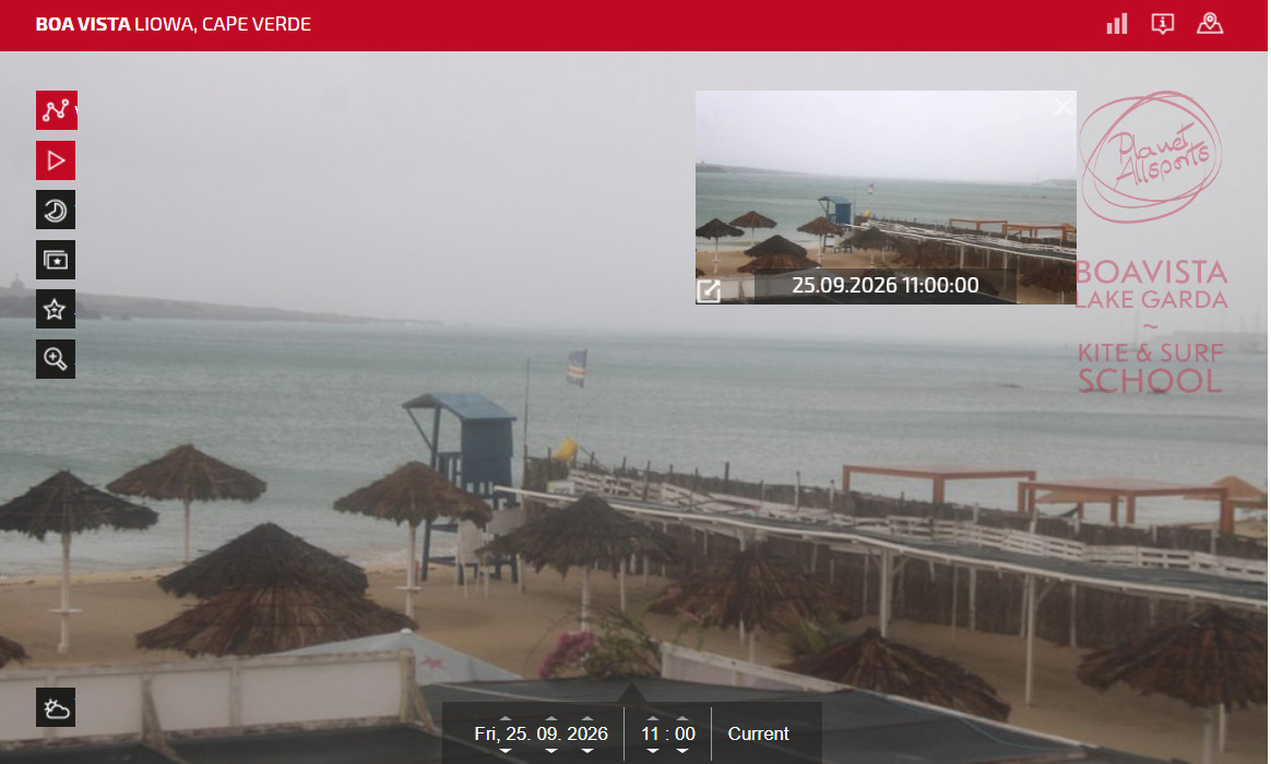 Foggy beach scene with thatched umbrellas, wooden deck, and calm ocean under overcast sky.