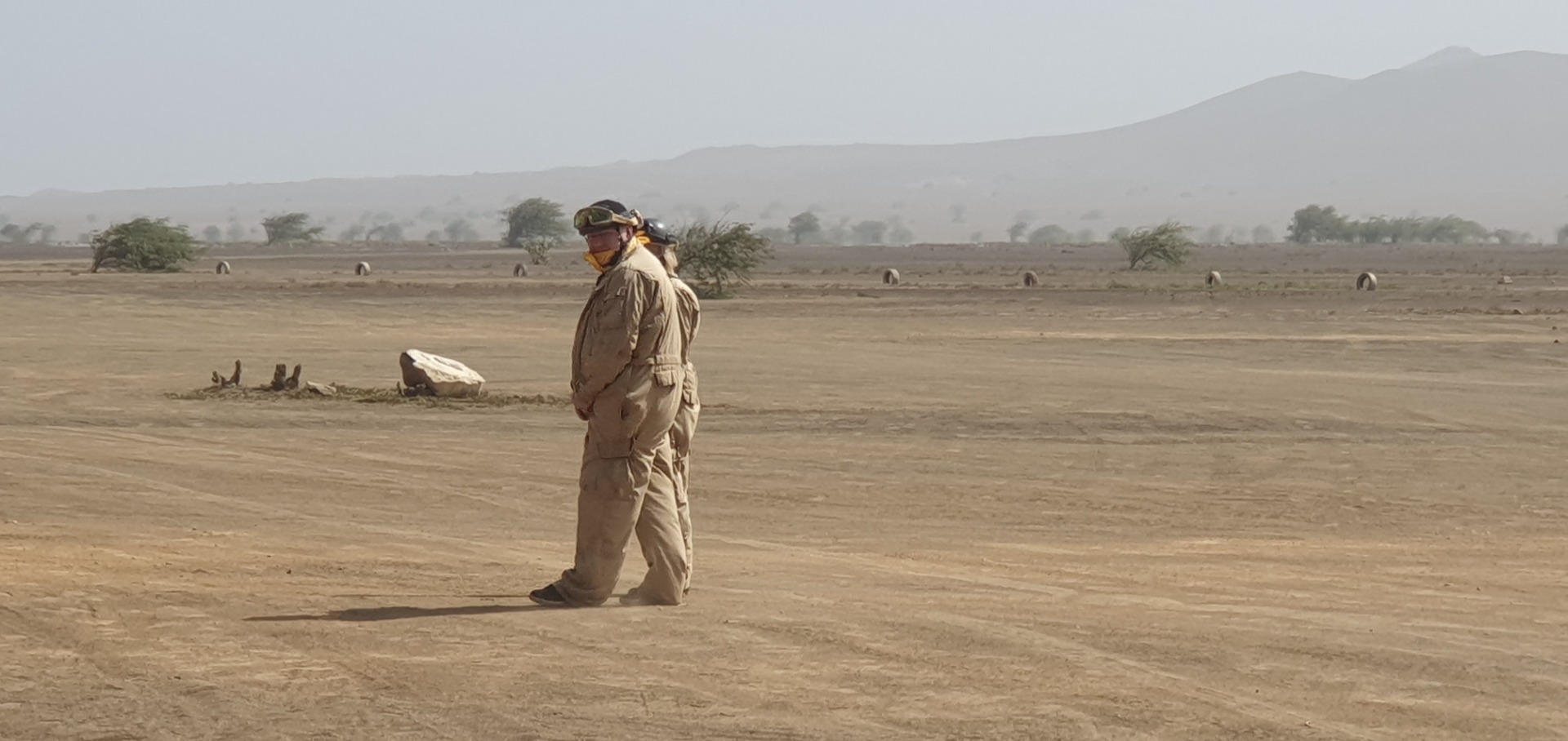 Sal - Cabo Verde - Terra Boa  - Mann in Schutzkleidung steht in einer staubigen Wüstenlandschaft, im Hintergrund mehrere Fahrzeuge und Hügel.